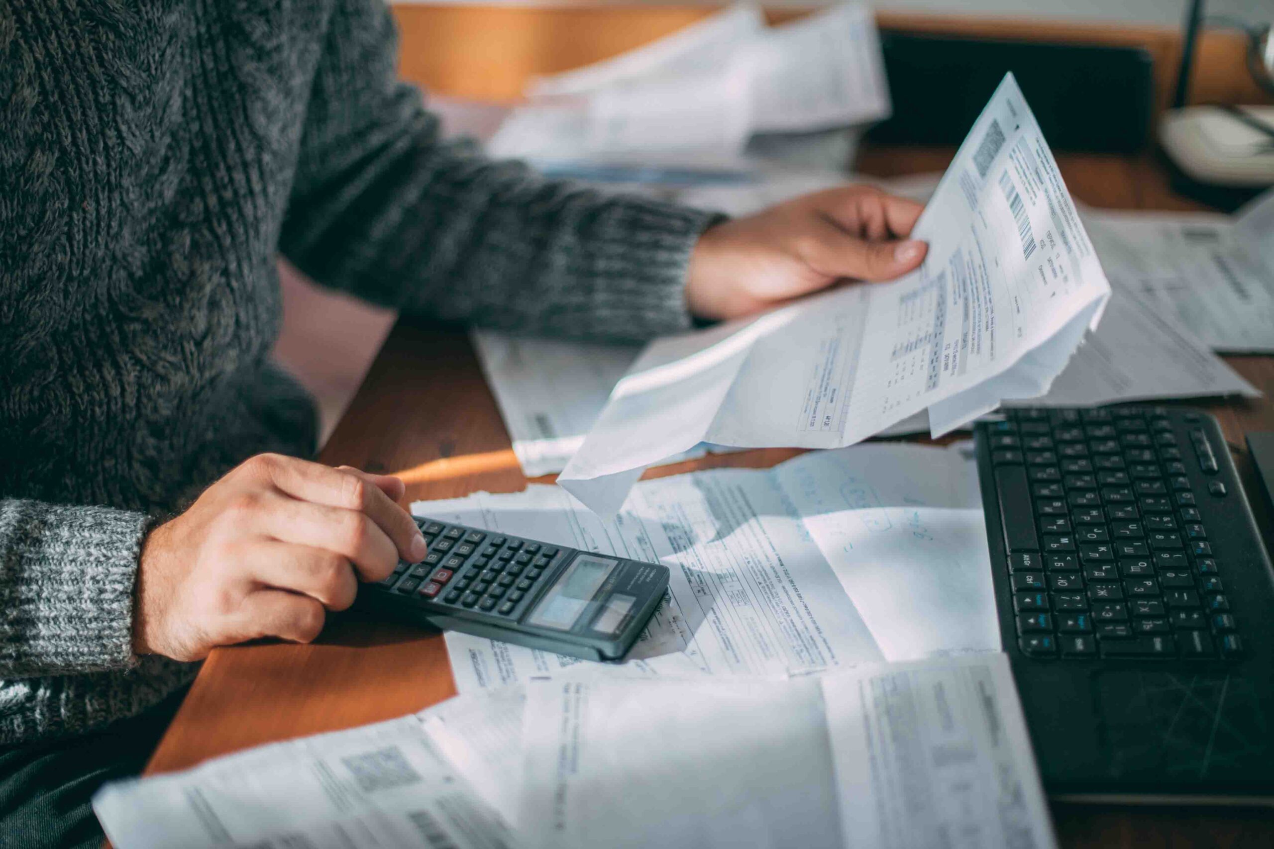 Close-up of male hands with a utility bill, a lot of checks and AdobeStock 529027855 scaled